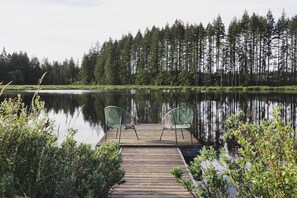 Une jetée en bois s’avance sur un lac paisible, avec deux chaises placées face à l’eau.