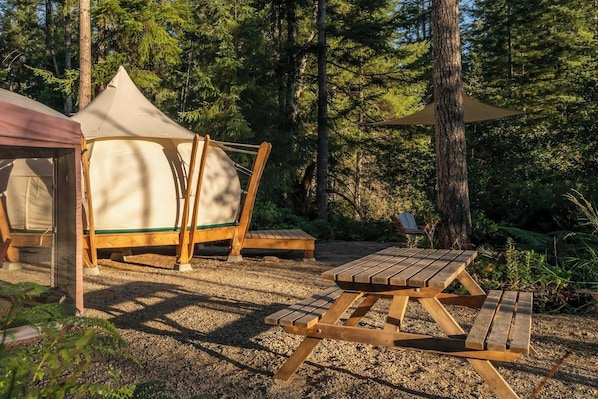 A campsite with a tent, a picnic table, and a chair.
