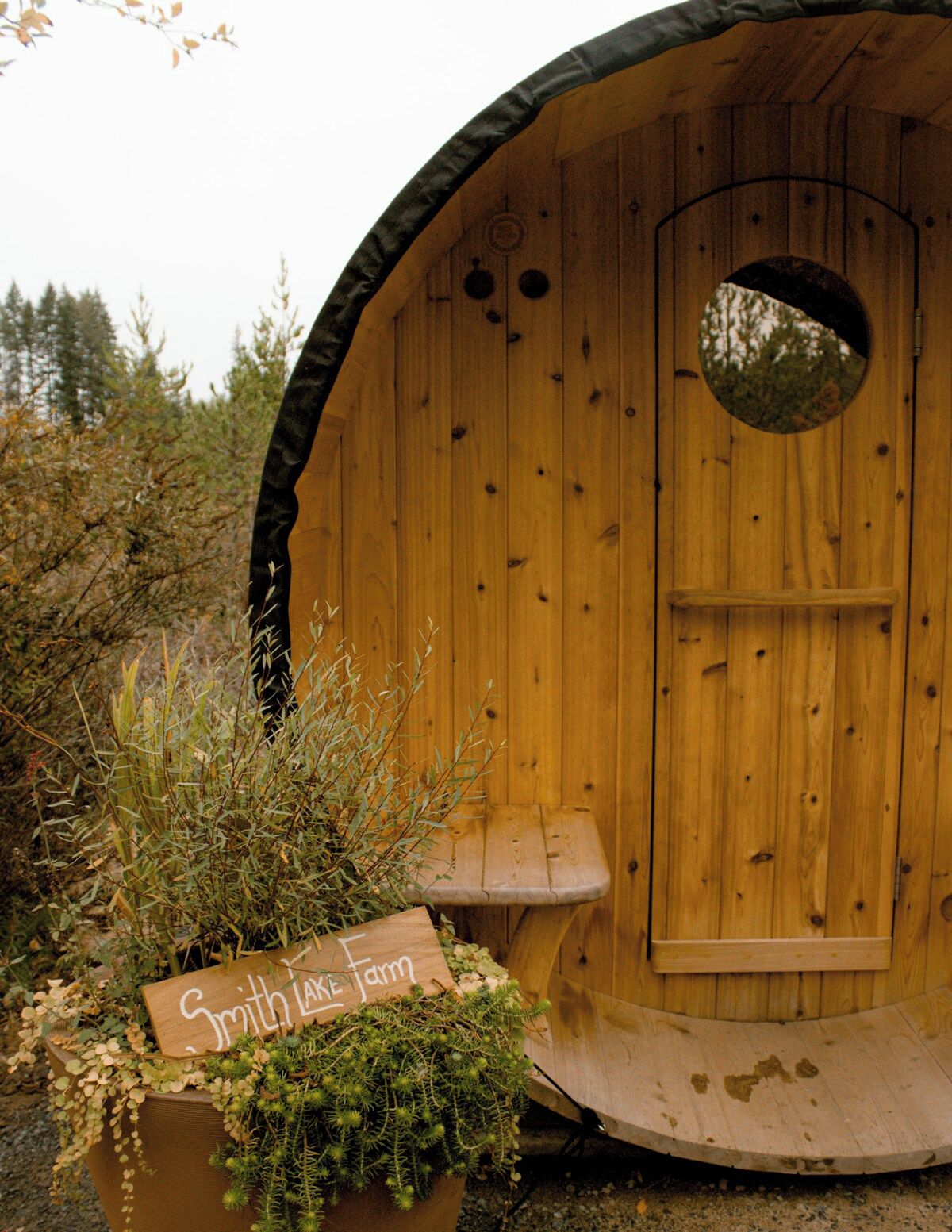 Una struttura in legno con una porta circolare e una piccola panchina all'esterno.