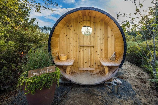 A wooden barrel-shaped structure with a bench inside, a small window, and a sign that reads 'Smith Lake Farm'.