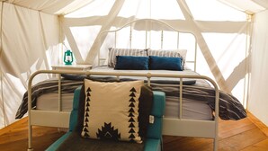A tented accommodation with a single bed, a nightstand, and a lantern. - Lake Front Farm, Glamping & Sauna Experience (Merville)