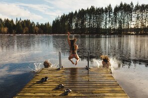 A wooden dock extending into a calm lake with a forest in the background. - The Foxglove Glamping Tent (Merville)