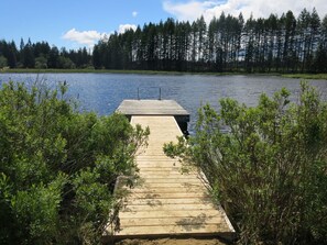 A wooden dock extending into a lake surrounded by dense forest.