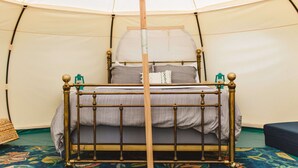 Ein Zelt mit einem Bett, einem Holzpfosten in der Mitte und einem gemusterten Teppich.