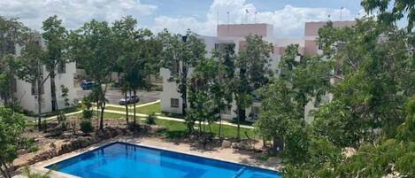A swimming pool surrounded by trees and buildings.