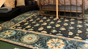 Een tent met een bed, kussens en een kamerkleed met een patroon.