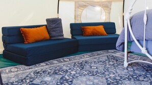Una habitación con dos sofás azules, cada uno con un cojín naranja, y un tapete azul estampado en el suelo.