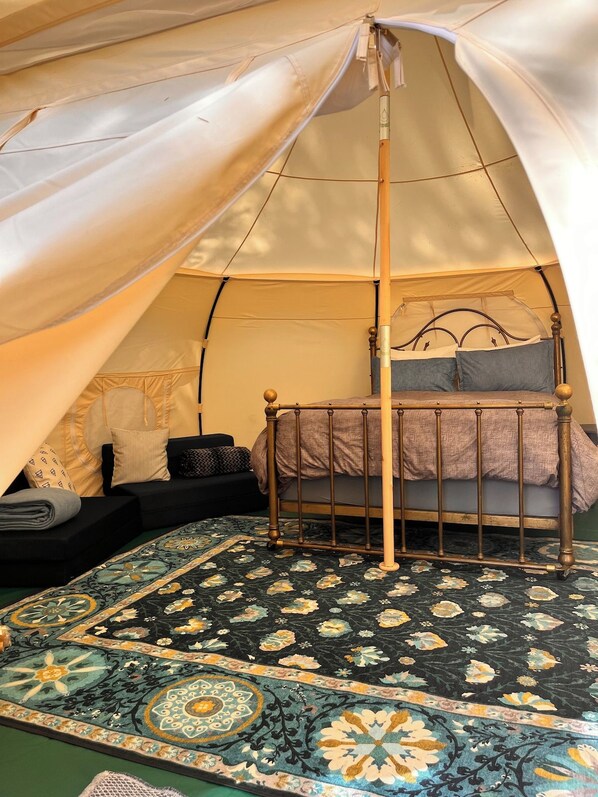 A tent with a bed, pillows, and a patterned rug.