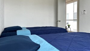 Un dormitorio con cama, puerta y vista al exterior.