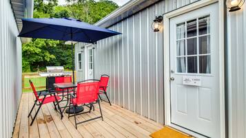 A covered patio with a table and chairs, a grill, and a door labeled "Cabin".