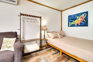 A bedroom with a bed, a chair, a lamp, a wall-mounted rack, and a painting.