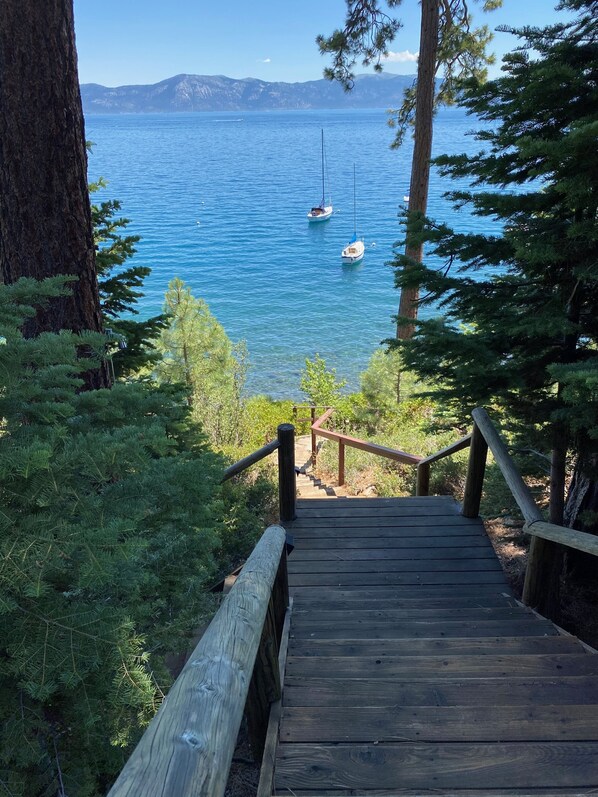 A wooden staircase leading to a viewpoint overlooking a calm lake with boats. - Rustic Lake Front Family Cabin with Beautiful Views (Carnelian Bay)
