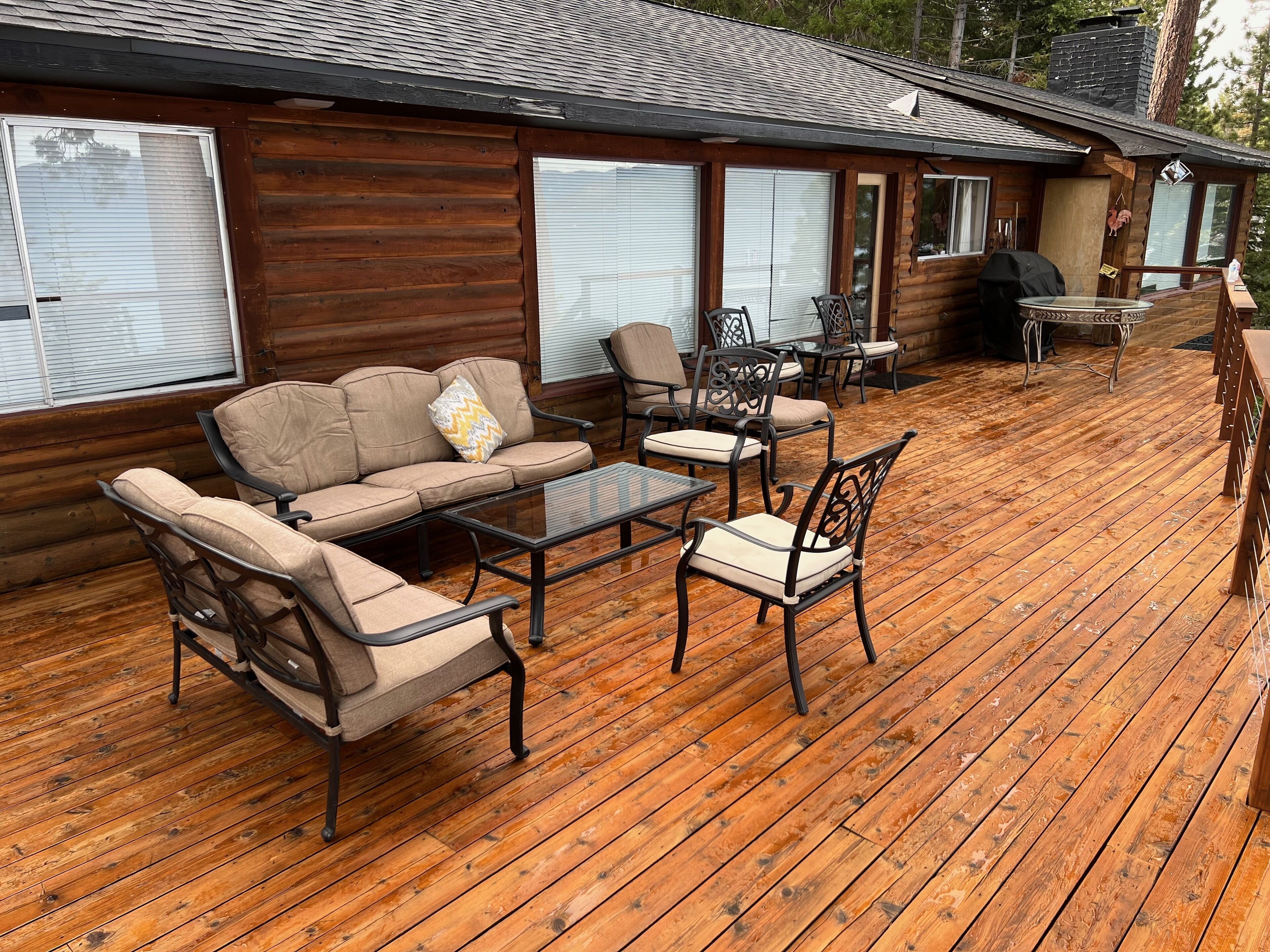 Eine Holzterrasse mit einer Couch, Sesseln und einem Tisch.