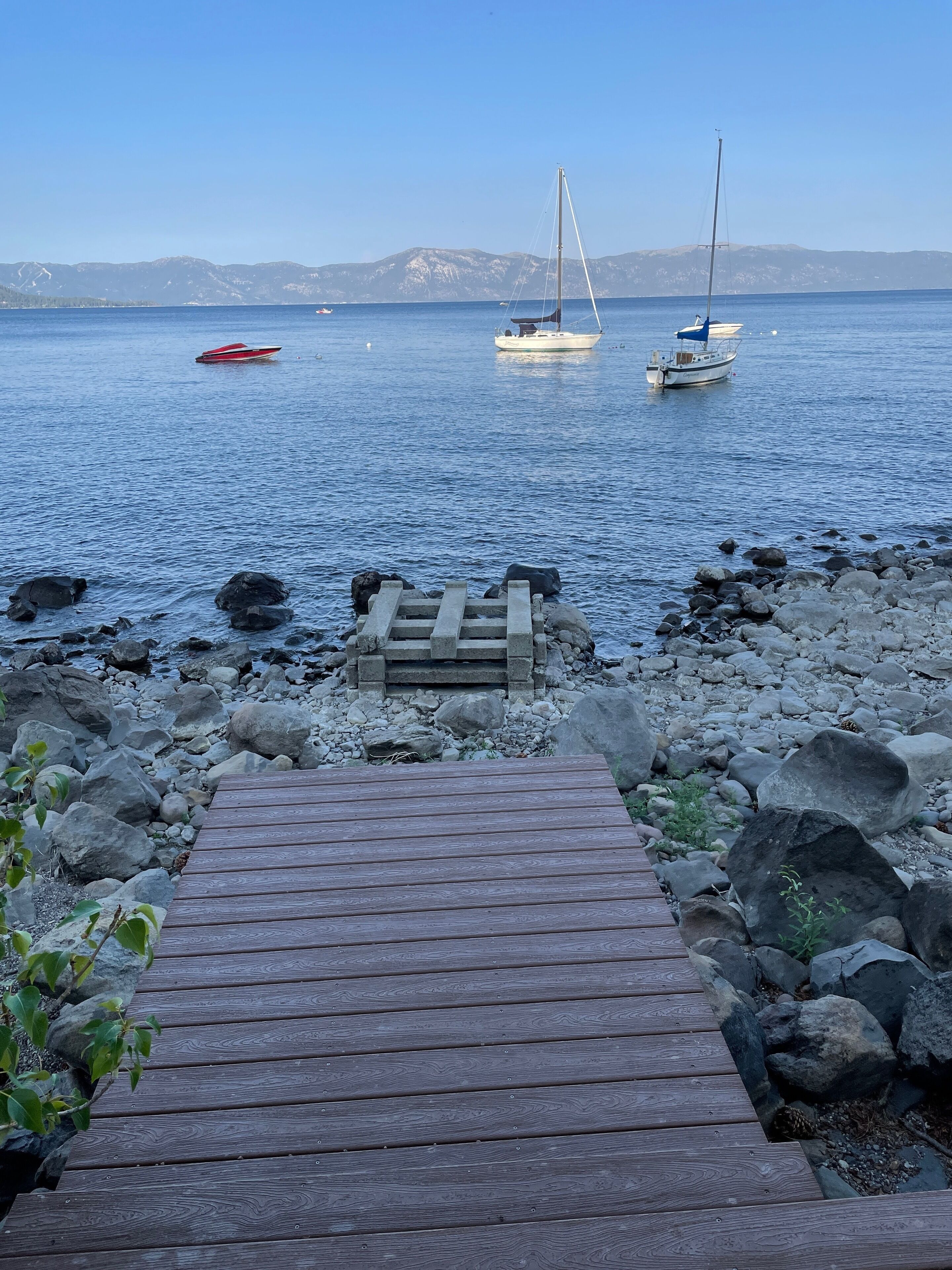 Un muelle de madera que da a una costa rocosa con barcos en el agua.