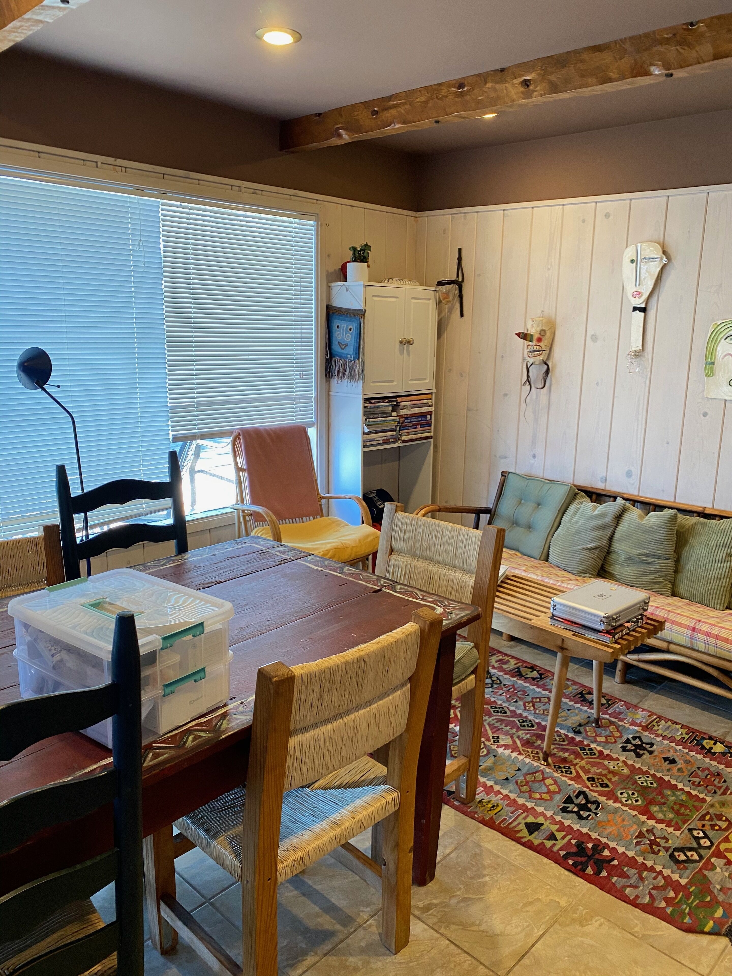 Una sala de estar acogedora con una mesa de madera, sillas, un sofá y una estantería.