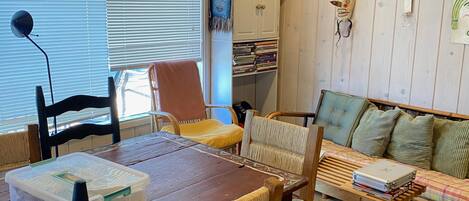 Una sala de estar acogedora con una mesa de madera, sillas, un sofá y una estantería.