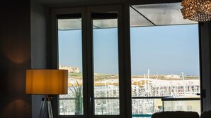 A room with a large window offering a view of a marina and buildings. - Marina with a view / 2 bd flat (Brighton and Hove)