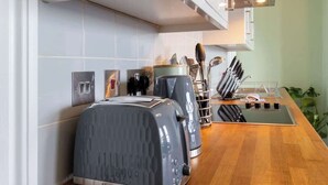 A modern kitchen with two toasters, a coffee maker, and a knife block. - Sea Breeze - 1 bedroom flat (Brighton and Hove)