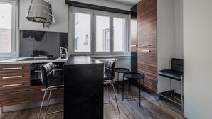 Eine moderne Küche mit einer zentralen Kochinsel, Barhocker und einem großen Fenster, das für natürliches Licht sorgt.