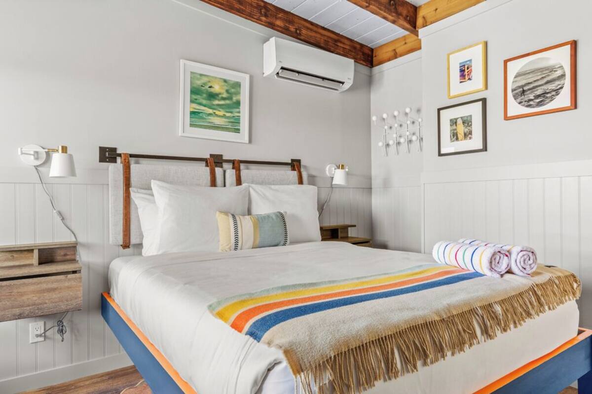 A neatly arranged bedroom with a bed, bedside tables, and a wall-mounted air conditioner.