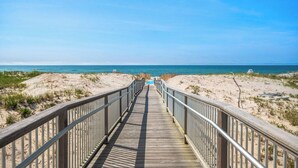 A wooden boardwalk leading to a beach with a clear sky. - The Inn Spot (Hampton Bays)
