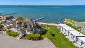 A coastal hotel with a dock extending into the water, a grassy lawn, and multiple buildings with balconies. - The Inn Spot (Hampton Bays)