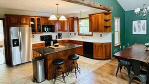 Una cocina con armarios de madera, un refrigerador de acero inoxidable, una isla central con taburetes y una cornamenta de ciervo colgada.