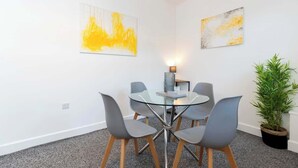 Un salón de conferencias con una mesa de vidrio, sillas grises y dos pinturas abstractas en las paredes.