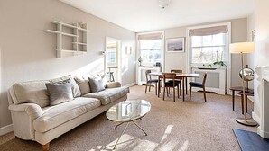 A living room with a sofa, coffee table, and dining area. - Beautiful One-Bedroom Apartment In Notting Hill (London)