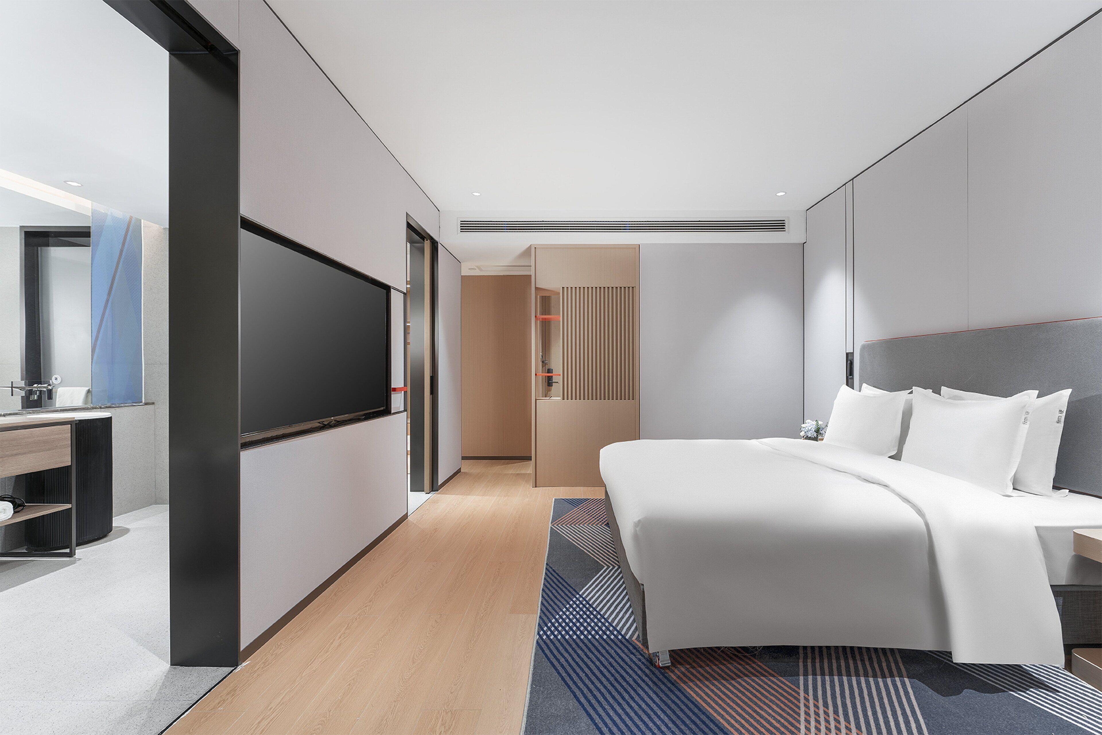 Et moderne hotelværelse med en stor seng, et fladskærms-tv, et skrivebord og et walk-in closet.