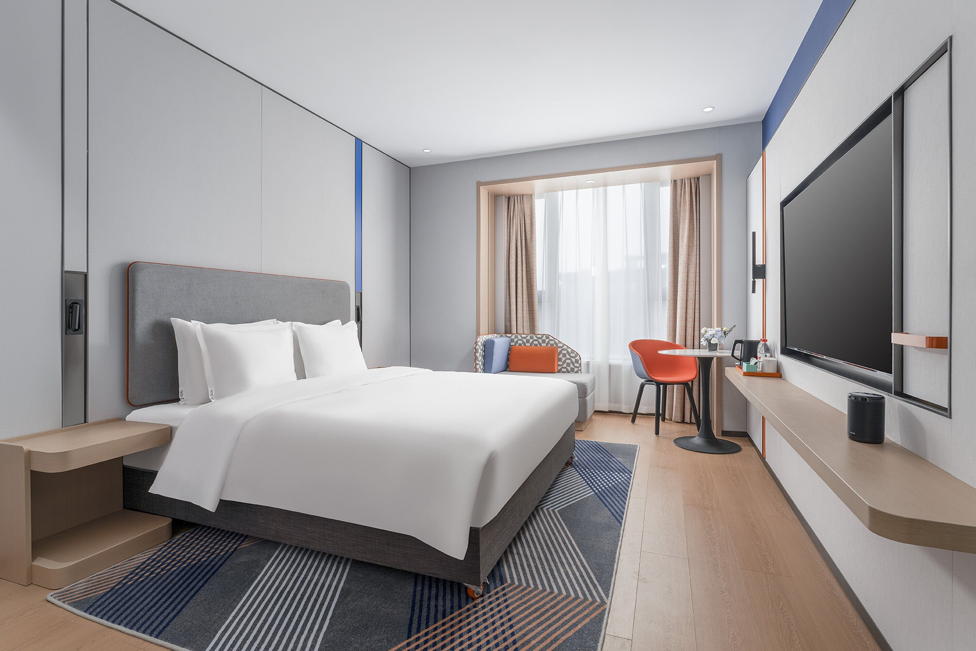 Een moderne hotelkamer met een groot bed, een bureau, een stoel en een televisie.