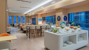 A modern dining area with a central buffet, multiple seating arrangements, and large windows providing natural light. - Holiday Inn Express Changsha Yuhua by IHG (Changsha)