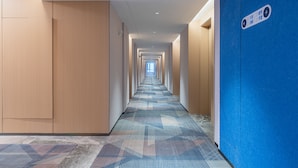 A long, narrow hotel corridor with wooden walls and a patterned carpet. - Holiday Inn Express Changsha Yuhua by IHG (Changsha)