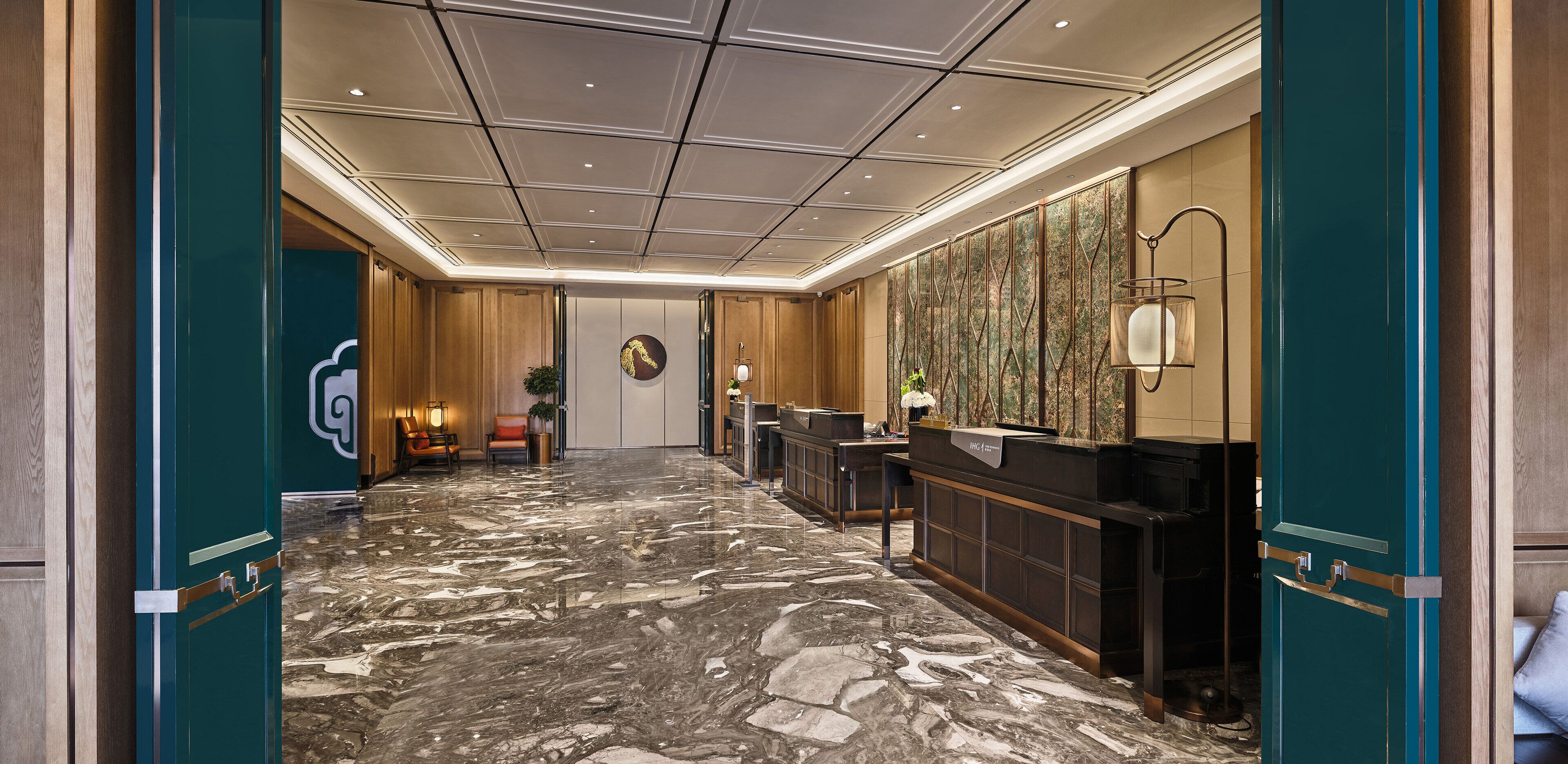 Un hall d’hôtel doté d’un sol en marbre, de lambris en bois, d’un comptoir de réception et d’une grande œuvre d’art accrochée au mur.