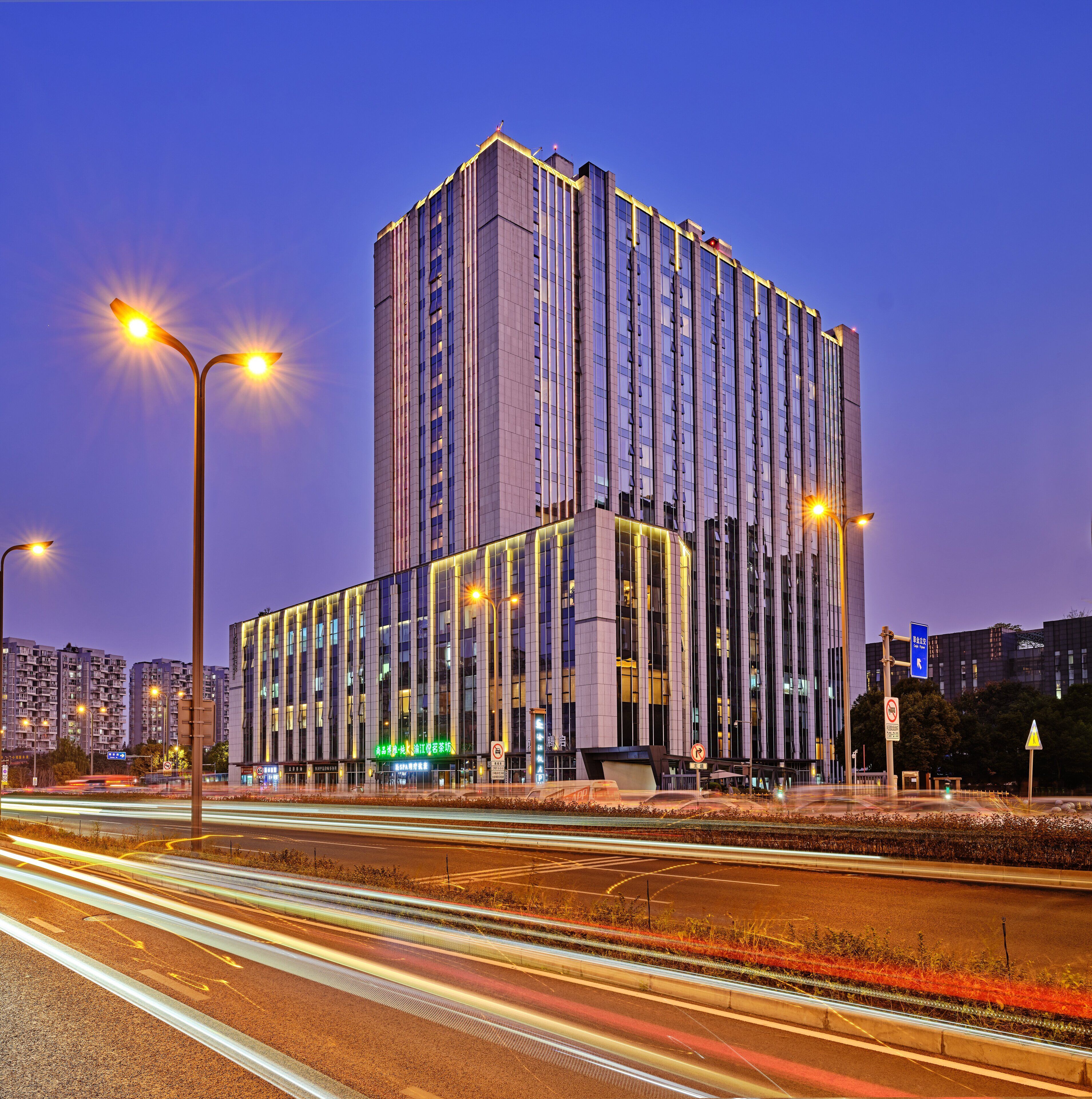 A high-rise building with a modern architectural design, featuring a prominent vertical structure and illuminated windows.