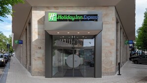 Een Holiday Inn Express gebouw met een modern ontwerp, met een grote glazen ingang en een opvallend bord boven de deur.