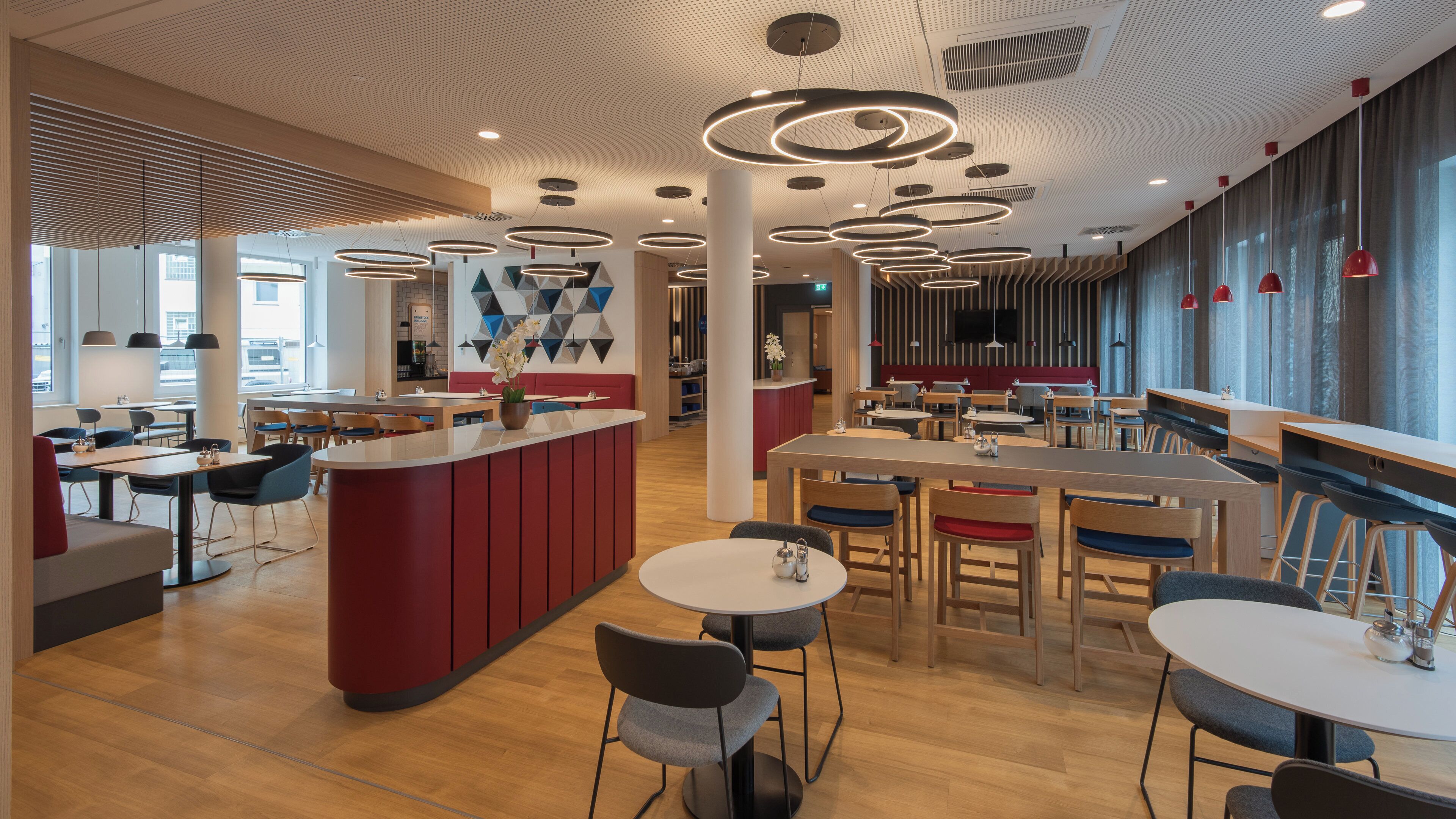 A modern restaurant with a central island, round tables, and a mix of seating styles.