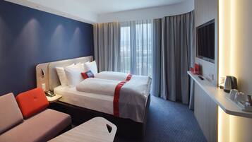 A hotel room with a bed, a desk, a chair, and a TV.