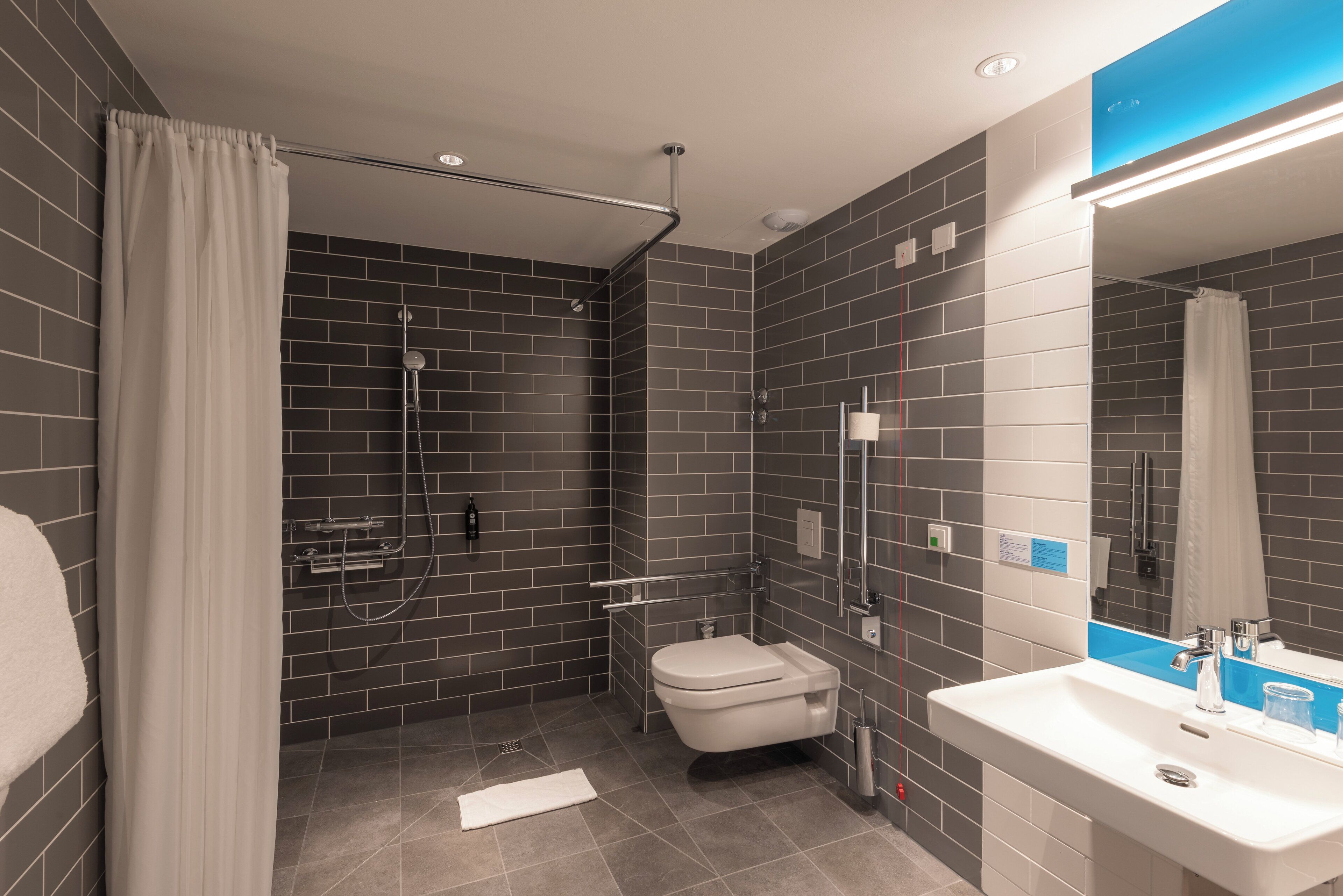 A modern bathroom with a shower, toilet, and sink.