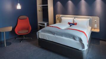 Una habitación de hotel con una cama, una silla roja, un armario y una mesita de noche.