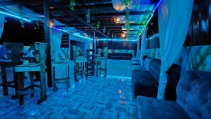 An indoor space with wooden furniture, a patterned floor, and hanging lights. - 696 Arena Aflao (Aflao)