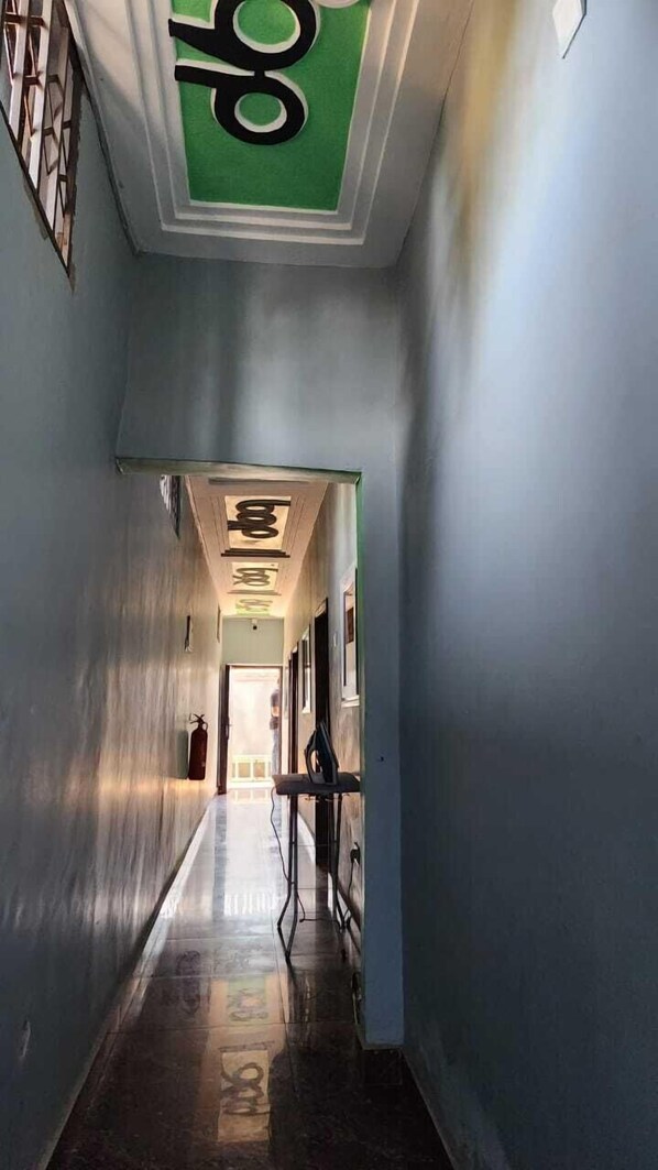 A hallway with a green ceiling and a fire extinguisher on the wall.