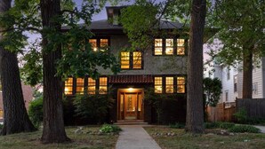 A two-story house with a central entrance, surrounded by trees and a well-maintained lawn. - Just A Short Stroll to Lake Harriet & Restaurants! (Minneapolis)