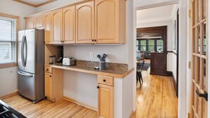 A kitchen with wooden cabinets, a stainless steel refrigerator, and a countertop with kitchen appliances. - Just A Short Stroll to Lake Harriet & Restaurants! (Minneapolis)