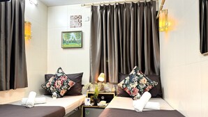 A hotel room with two beds, dark curtains, a small table with a lamp, and a picture on the wall. - International Inn (Kowloon)