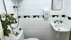 A small bathroom with a toilet, sink, and shower. - International Inn (Kowloon)