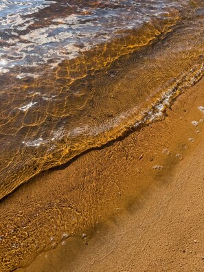 A close-up of a sandy beach with clear water. - Chalet l'Oasis plage et spa creusé privé (Mandeville)
