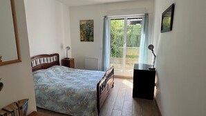 Ein Schlafzimmer mit einem Bett, einem Schreibtisch, einem Stuhl, einem Fenster mit Vorhängen und einem Bild an der Wand.