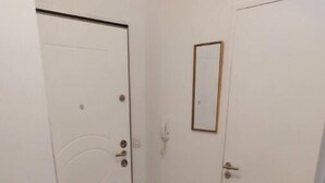 Ein Flur mit zwei weißen Türen, eine davon mit einem runden Muster, und einem kleinen Spiegel an der Wand.