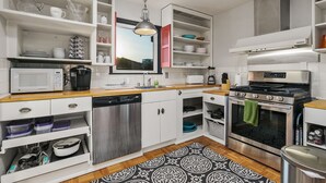 A modern kitchen with white cabinetry, a stainless steel dishwasher, a built-in oven, and a microwave.